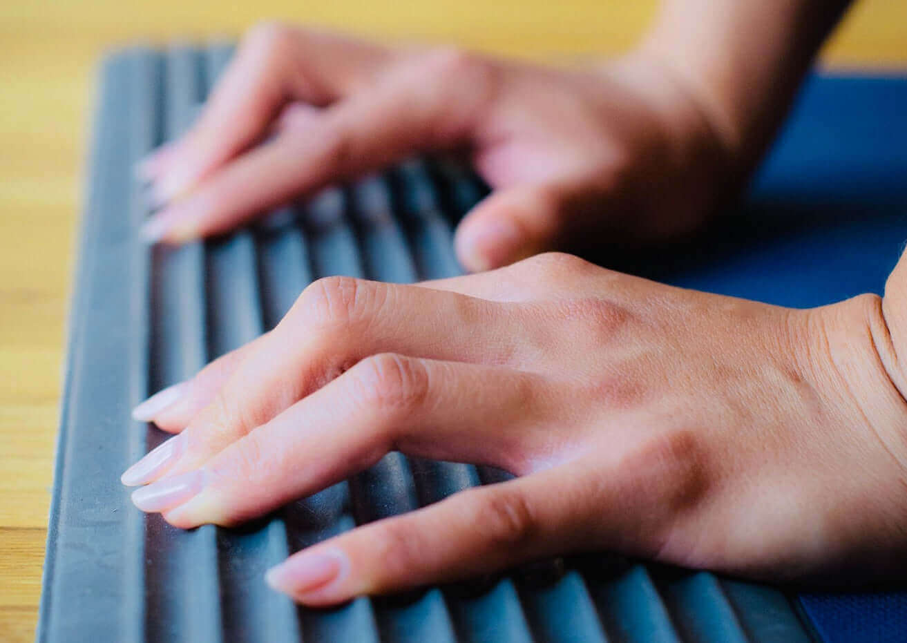 A close up of a woman's hands on the acupressure ridges of Kinshe Yoga's 3 dimensional yoga mat called the "Ridge Mat".