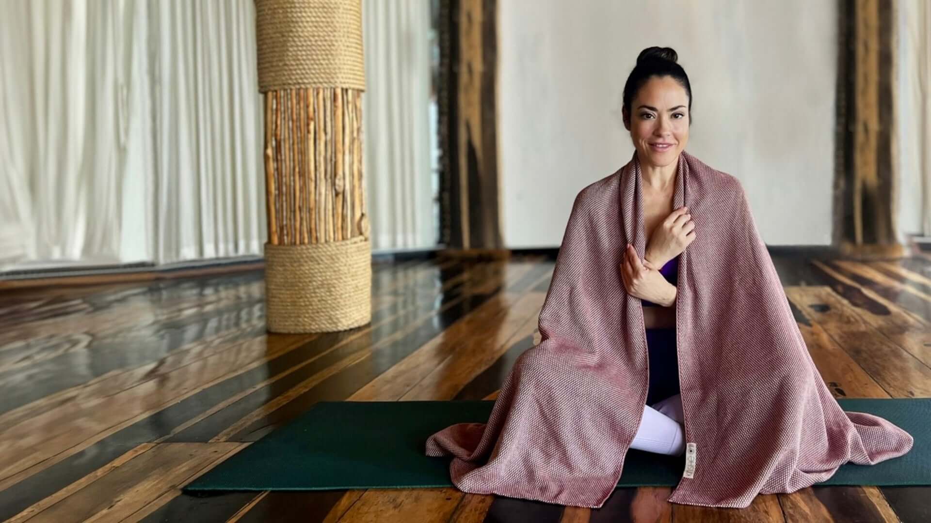 Yogini sits on a yoga mat with a garnet colored, 100 percent premium turkish cotton  yoga towel draped around her.  