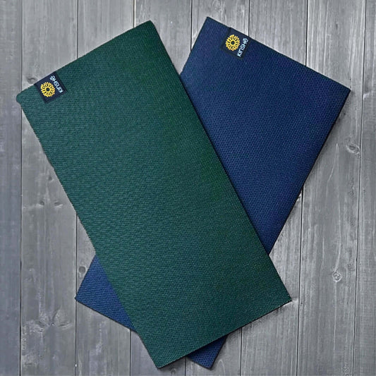 Kinshē Yoga's mini yoga mats are fanned out on grey wood deck.   Colors are Jewel Forest Green and Neptune Blue.
